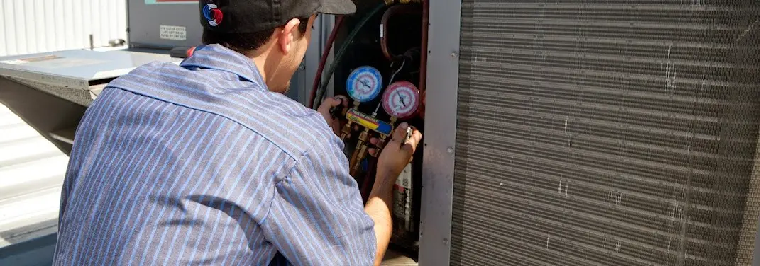 HVAC technician servicing a condenser unit in Wolfforth