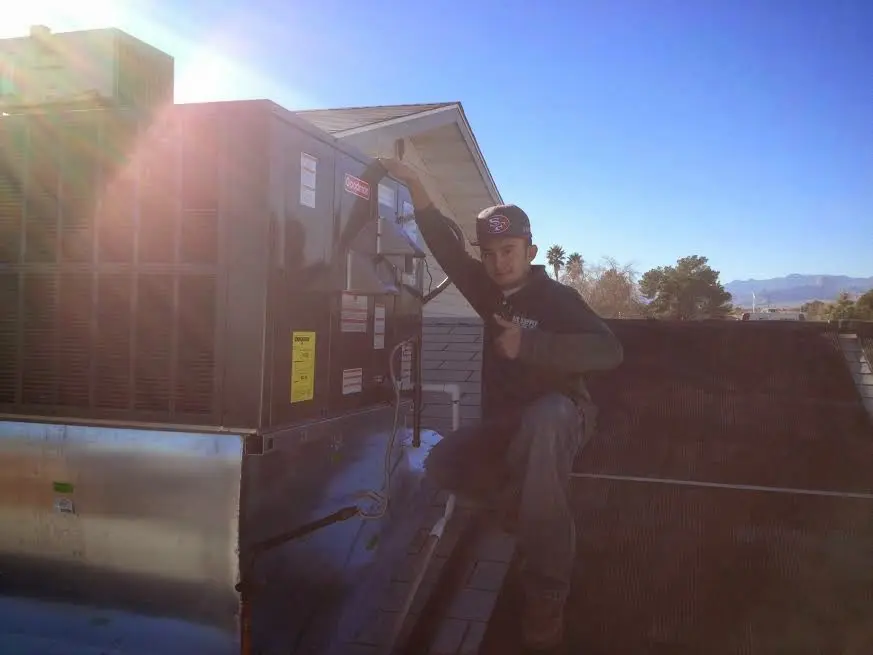 HVAC technician performing AC Tune-Up on a rooftop unit in Wolfforth
